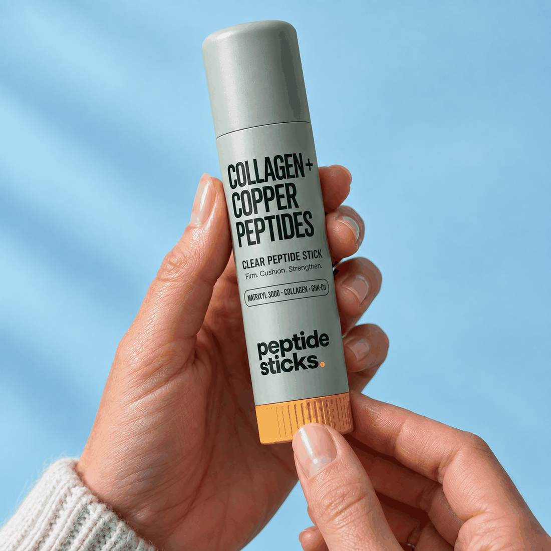 A hand holding the Peptide Sticks™ Collagen + Copper Stick